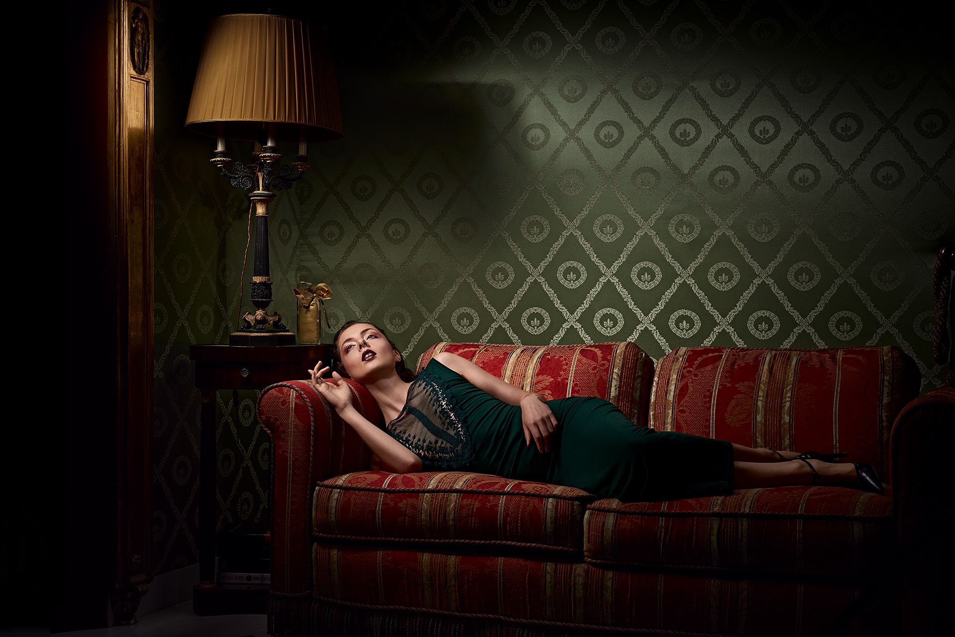 "Lady on the red sofa". A stage photography portrait in flash light.